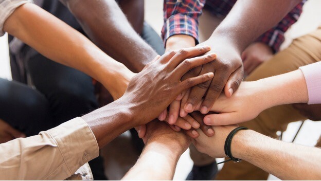a circle of people with hands in the middle to cheer