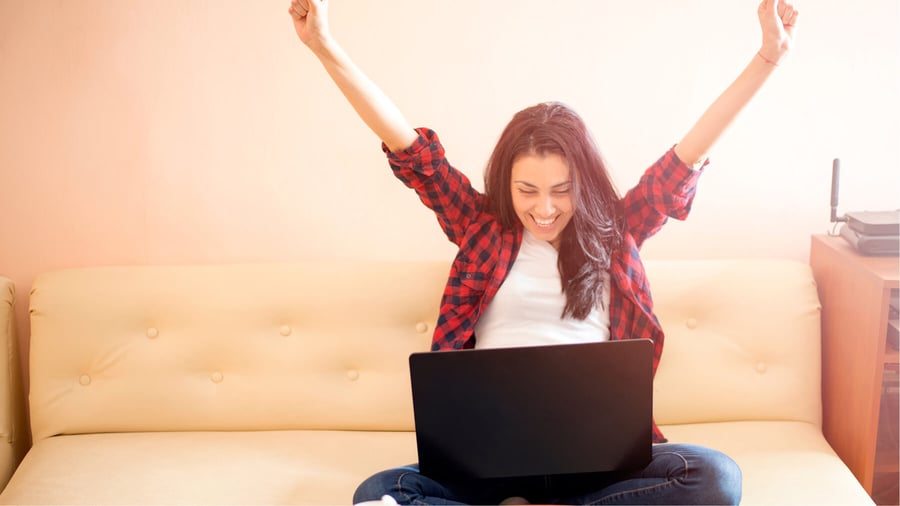 Blog Post Hero: a woman on her laptop, celebrating, with arms raised