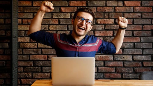 Blog Post Thumbnail: a young man on his computer celebrating success