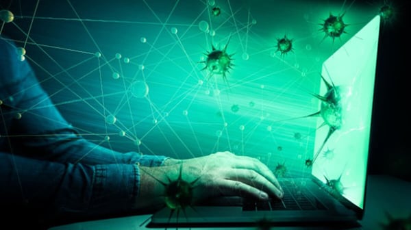 Blog Post Hero: a close-up of a person's hands typing on a laptop keyboard that emits a glowing green light. The screen is superimposed with graphics of stylized green virus particles and interconnecting lines, suggesting the theme of digital connectivity and cybersecurity threats