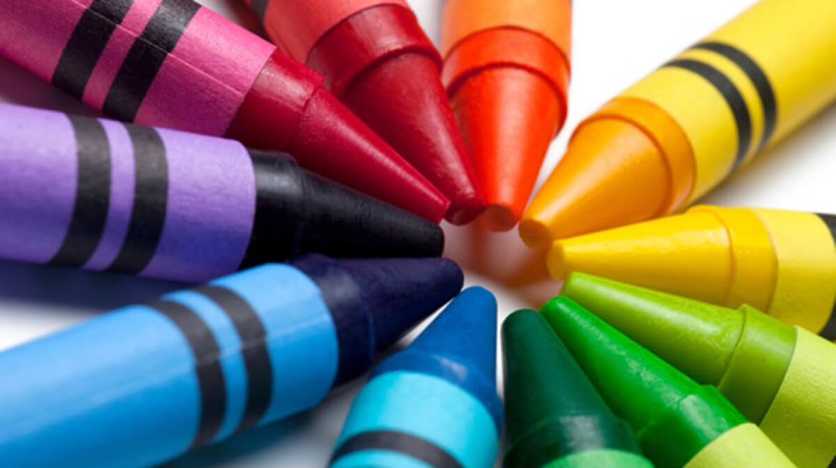 a vibrant collection of crayons in various colors closely grouped together, with the tips pointing towards the center. The crayons appear new with sharp tips, indicating they have not been used much, if at all. The range of colors and the waxy texture are characteristic of crayons commonly used for drawing and coloring, especially by children.