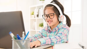 Blog Post Hero: a young girl wearing headphones working on the computer
