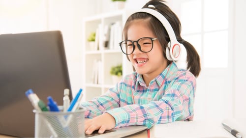 Blog Post Thumbnail: a young girl wearing headphones working on the computer
